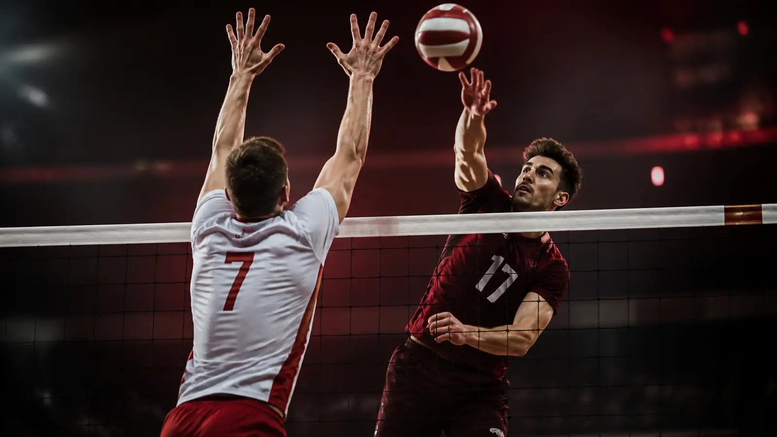 Dorośli siatkarze przy siatce w hali sportowej